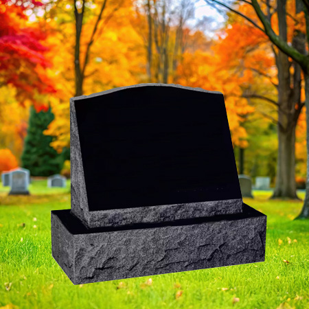 "Black granite slant upright headstone with polished face and chiseled edge finishes, mounted on a granite base in a peaceful autumn cemetery setting."