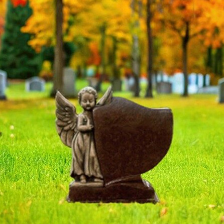 "Brown granite upright headstone with carved angel beside shield tablet on polished base—crafted for spiritual dedication."