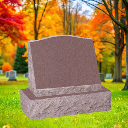 "Red salmon granite slant upright headstone with polished face and chiseled edge finishes, mounted on a granite base in a peaceful autumn cemetery setting."