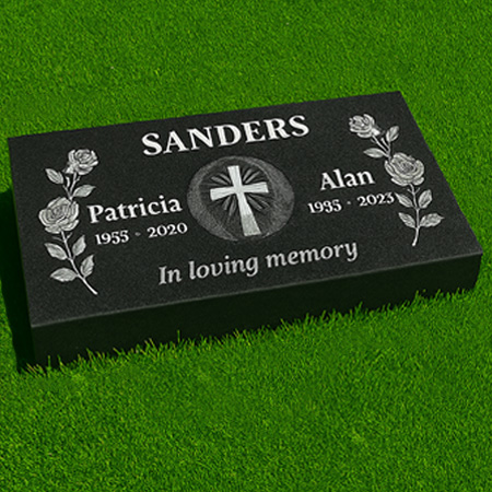 "Black granite pillow flush grass marker with patterned cross centerpiece, rose carvings, and companion inscription panels." 
