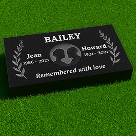 "Black granite pillow flush grass marker with laurel motif, facing silhouette portraits, dual inscription panels, and heartfelt epitaph."