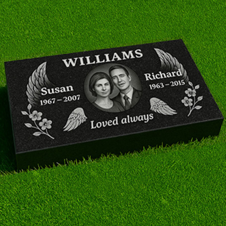 "Black granite pillow flush grass marker with winged oval portrait frame, floral carvings, and companion inscriptions for shared remembrance."