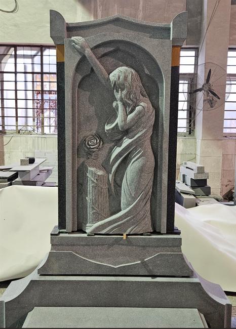 Stone sculpture of a mourning woman with carved rose and column, set in Elhasg’s memorial workshop.