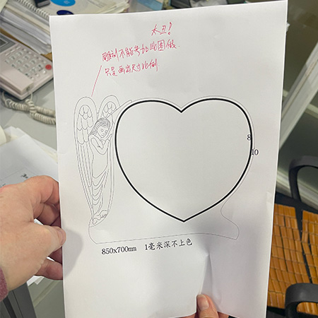 "Hand holding a memorial design sketch with personalized inscriptions, font selections, and layout notes for a double headstone."