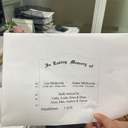 "Printed memorial inscription proof with names, dates, and family tributes, marked with red checkmarks and handwritten approval."