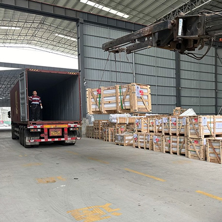 "Crated memorials and stone slabs lifted by crane into a shipping container inside an industrial warehouse, with professional handling and global logistics."