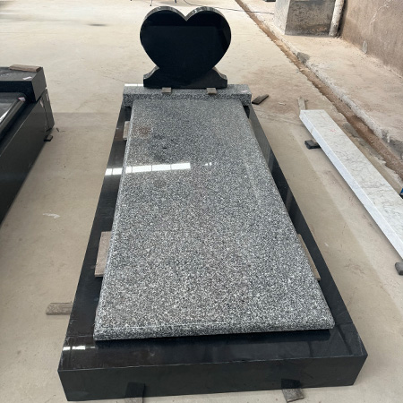 "Heart-shaped black granite headstone with speckled gray granite ledger and rectangular base, photographed in ELHASG workshop surrounded by stone materials."