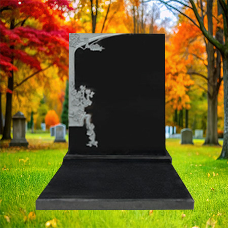 "Polished black granite upright headstone with floral carving on the upper left corner, mounted on a polished granite base."