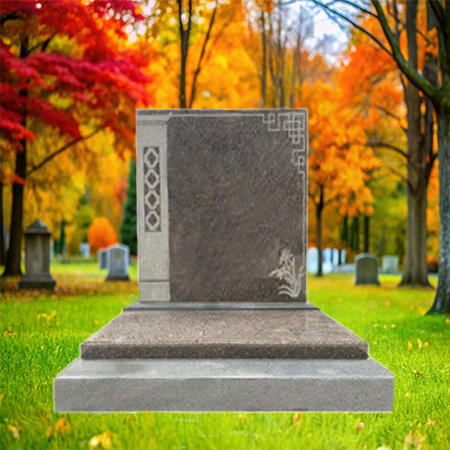 "Polished granite upright headstone with decorative carvings running down both sides, mounted on a multi-tiered granite base."