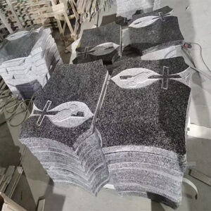 "Multiple polished granite upright headstones with Christian cross, Ichthys, and praying hands in batch production at Elhasg factory."
