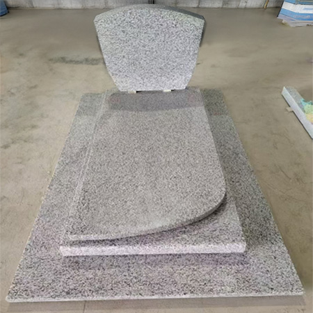 "Grey polished granite upright headstone with curved top and multi-layered ledger base."