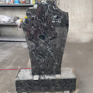 Granite flat marker memorial with heart-shaped design and engraving outlines, photographed in workshop.
