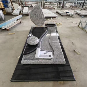 "Black and grey polished granite upright headstone with leaf-shaped design and wave-contoured ledger base."