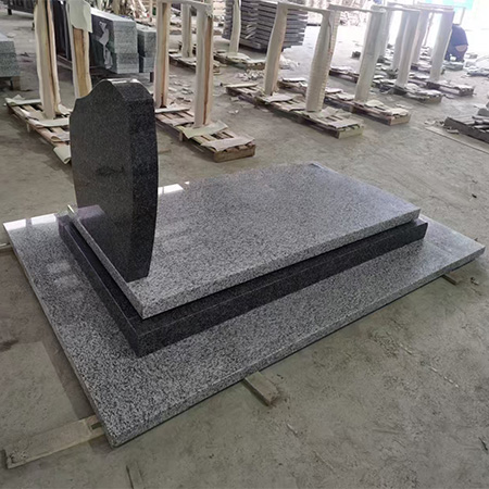 "Grey and black polished granite upright headstone with rounded top and flat ledger base."