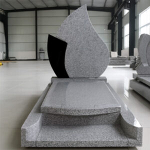 "Teardrop-shaped upright headstone in speckled light gray granite with partial black accent and full-length ledger."