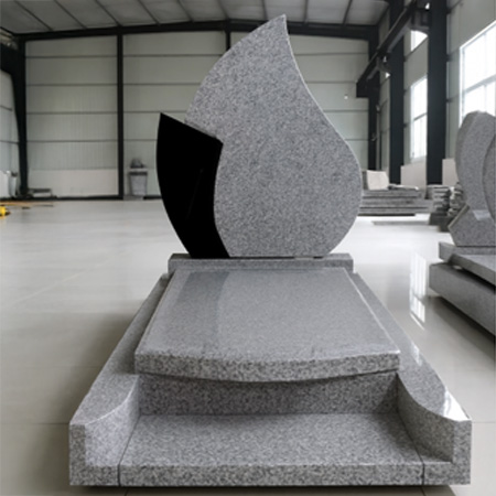 "Teardrop-shaped upright headstone in speckled light gray granite with partial black accent and full-length ledger."