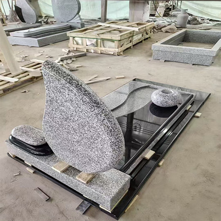 "Teardrop-shaped upright headstone in speckled gray granite with full-length polished black granite ledger and sculptural vase."