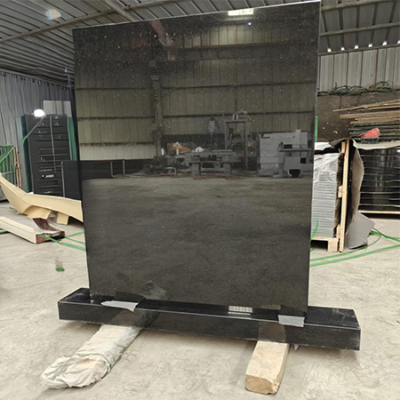 "Polished black granite headstone mounted on base with technician in Elhasg workshop."