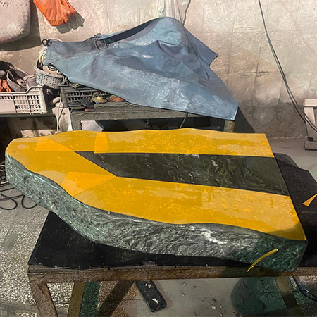 "Granite headstone with diagonal stripe design and chiseled edge on workbench in Elhasg workshop."