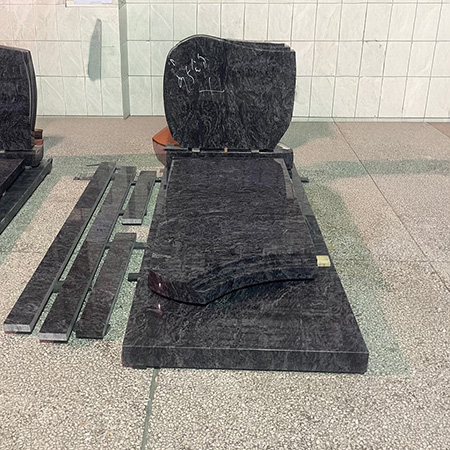 "Modern granite headstone with full ledger tomb cover in Elhasg workshop surrounded by tools and materials."