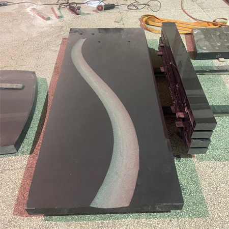 "Curved polished granite ledger tombstone cover in Elhasg workshop surrounded by tools and stone fragments."