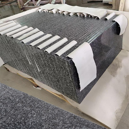 "Polished granite slabs stacked with protective sheets in Elhasg factory for headstone and ledger use."