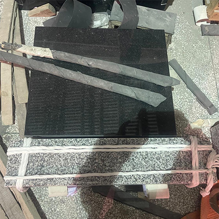 "Polished granite headstone and base tied with rope and surrounded by tools in Elhasg workshop."