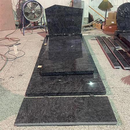 "Polished granite headstone with full ledger tomb cover in Elhasg workshop surrounded by tools and materials."