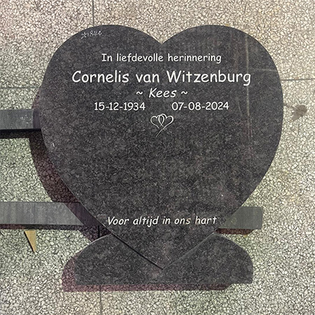 "Polished heart-shaped black granite headstone with Dutch inscription on tile floor in Elhasg workshop."