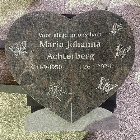 "Heart-shaped granite headstone with Dutch inscription, butterfly and flower engravings in Elhasg workshop."
