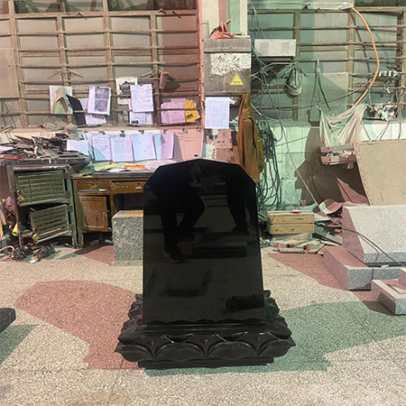 "Polished black granite tombstone with carved base in Japanese style, crafted at Elhasg workshop."