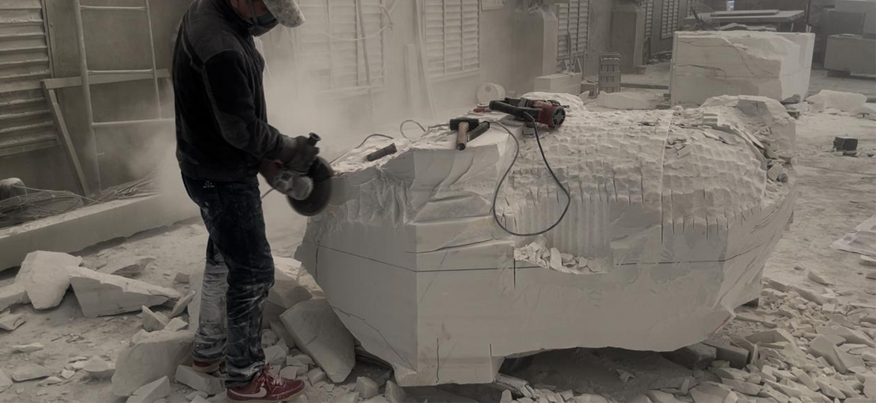 "Artisan hand-carving a marble elephant statue in Elhasg workshop with tools and stone dust."