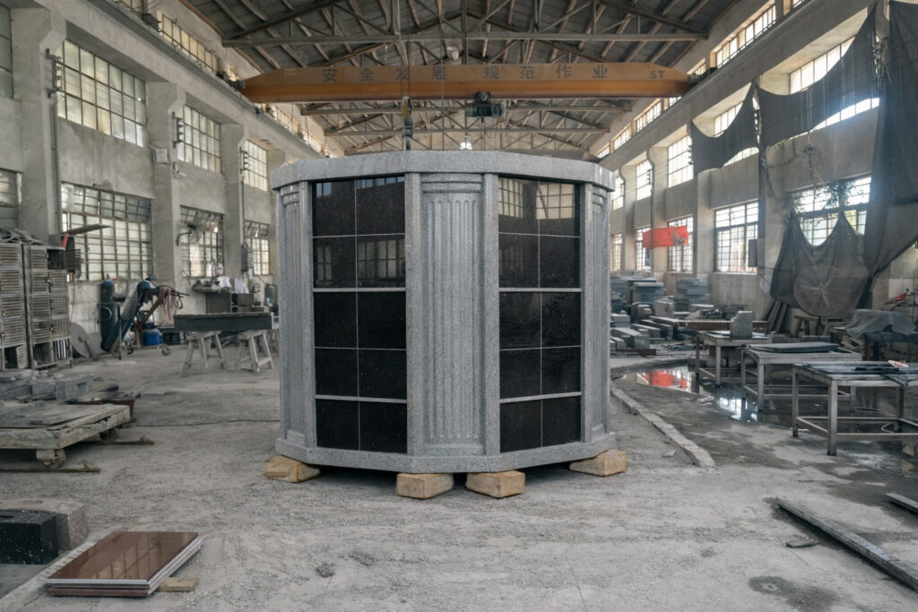 "Octagonal granite columbarium wall with polished niche panels and autumn chrysanthemums."